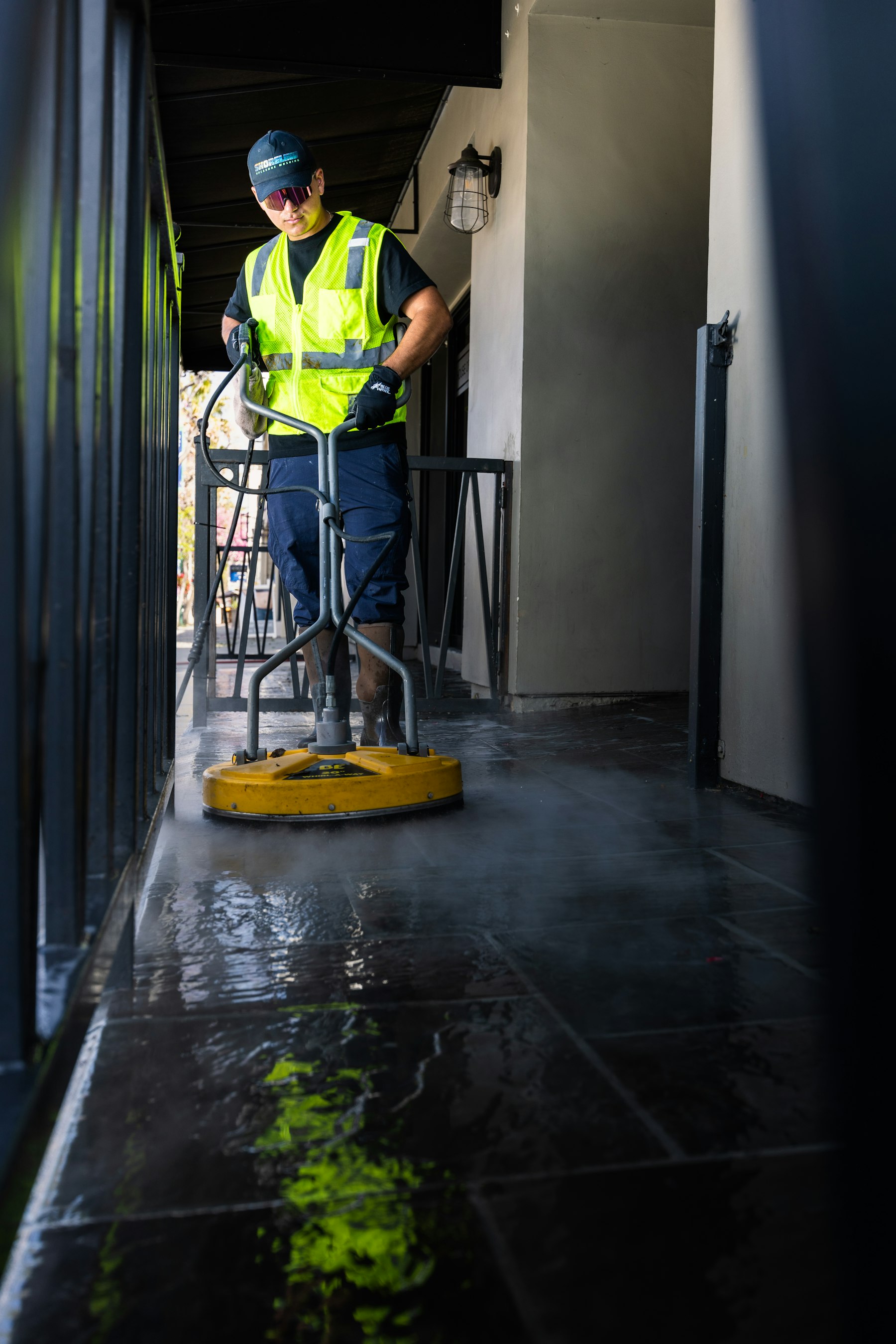 Technician in high-visibility gear power-cleaning a commercial floor